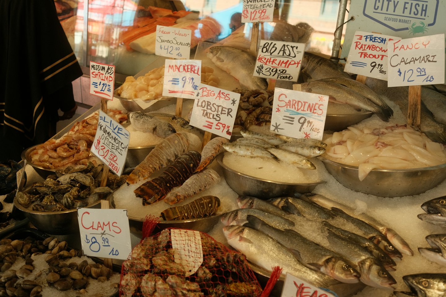 Fresh seafood on ice at a market stall with handwritten signs.
